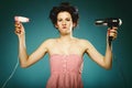 Funny girl in curlers with hairdryer styling hair