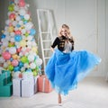 Funny girl dancing in blue skirt. Beautiful young woman blonde in a fabulous interior.