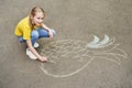 Funny girl draws on the pavement with chalk