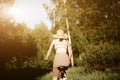 Funny girl driving bicycle outdoor. Sunny summer lifestyle concept. Woman in dress and hat in Field with dandelions Royalty Free Stock Photo