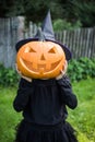 Funny girl with halloween pumpki in garden