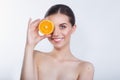Funny girl holding orange in front of her face and showing tongue on white background. Royalty Free Stock Photo