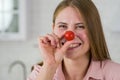 Funny girl holds a cherry tomato near her nose Royalty Free Stock Photo