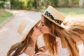 Funny girl with light-brown straight hair kissing mom during walk on the alley. Outdoor close-up portrait of lovely Royalty Free Stock Photo