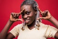 Funny girl makes frame of the fingers near the face. Photo of african girl with perfect skin on red background. Close up. Youth