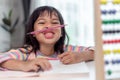 funny girl playing holding pen between nose and lips as mustache looking at the camera, playful bored after learning long hours Royalty Free Stock Photo