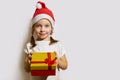 Funny girl in a Santa claus hat opens a Christmas gift, portrait of a girl on a white background Royalty Free Stock Photo