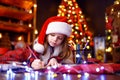 Funny girl in Santa hat writes letter to Santa Royalty Free Stock Photo