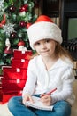 Funny girl in Santa hat writes letter to Santa Royalty Free Stock Photo