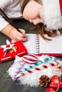 Funny girl in Santa hat writes letter to Santa near christmas de Royalty Free Stock Photo