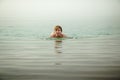 Funny girl swims in water of Dead Sea in Jordan and fog Royalty Free Stock Photo