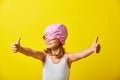 Funny girl in a swimsuit stands on a yellow background, shows thumbs up, wearing a swimming cap and glasses, portrait on Royalty Free Stock Photo