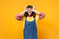 Funny girl teenager in french beret denim sundress holding hands near eyes imitating glasses or binoculars isolated on Royalty Free Stock Photo