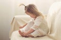 Funny girl toddler in white dress with a tail sitting on the sofa at home Royalty Free Stock Photo