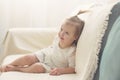 Funny girl toddler in white dress with a tail sitting on the sofa at home Royalty Free Stock Photo