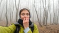 Funny girl traveler while walking through a dangerous foggy forest. Crooked trunks of bare trees in a thick fog. The woman`s hair Royalty Free Stock Photo