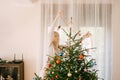 A funny girl tries to decorate a Christmas tree, throws a red garland on it.