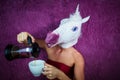 Funny girl unicorn pours tea. Freaky young woman in comical mask