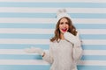 Funny, girl in warm hat and winter sweater makes surprised face. Slavic model poses for portrait on isolated background Royalty Free Stock Photo