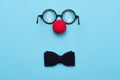 Funny glasses, red clown nose and tie lie on a colored background, like a face Royalty Free Stock Photo