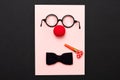 Funny glasses, red clown nose and tie lie on a colored background, like a face Royalty Free Stock Photo