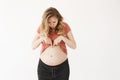 Funny good-looking pregnant european young woman with long light hair in comfy clothes looking at belly with interested Royalty Free Stock Photo