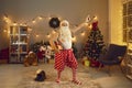 Funny granddad holding present and having fun on Christmas disco night party at home