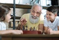 Funny grandfather smiling while playing chess with kids Royalty Free Stock Photo