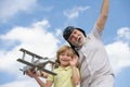 Funny grandfather and son playing with wooden plane against summer sky background. Child boy with dreams of flying or