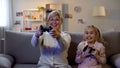 Funny grandma and girl playing video game with console, rejoicing victory, hobby