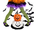 Funny green black Striped legs of a little girl with halloween costume of a witch with witch shoes and smiley halloween pumpkin