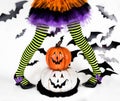 Trik or treat. Halloween kids. Striped legs of a little witch girl with happy smiley pumpkins