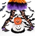 Funny black legs of a little girl with halloween costume of a witch with witch shoes and smiley halloween pumpkin