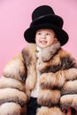 Funny grinning little boy in fur coat. He has put two classical hats on at once. Royalty Free Stock Photo