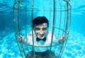 Funny groom underwater in a bird cage