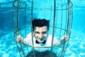 Funny groom underwater in a bird cage