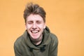 Funny guy looking into the camera and smiles against the background of the orange wall Royalty Free Stock Photo