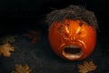 Funny halloween carved pumpkin into face expression, black background with copy space, creative squash carving for ghost night and Royalty Free Stock Photo