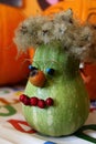 Funny halloween decoration - green pumpkin decorated with rose hips as nose and mouth, glasses made of copper wire