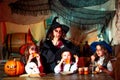 Funny Halloween. Funny kids in carnival costumes indoors. Group of little witch with a pumpkin and sweets. Halloween