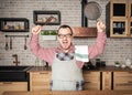 Funny handsome screaming angry man wearing pinafore with kitchen utensils