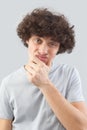 Funny and handsome, a young man with curly hair, he looks into the camera with his blue eyes, his hands on his face, a portrait of Royalty Free Stock Photo