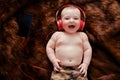 Funny happy baby boy listens to music in wired headphones online from his phone. Smiling child is lying in earphones, top view