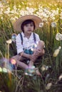 funny happy a beautiful boy child sit in hat on a field with white dandelions at sunset in summer. soap bubbles are Royalty Free Stock Photo