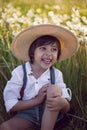 funny happy a beautiful boy child sit in hat on a field with white dandelions at sunset in summer. soap bubbles are Royalty Free Stock Photo