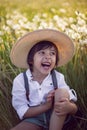 funny happy a beautiful boy child sit in hat on a field with white dandelions at sunset in summer. soap bubbles are Royalty Free Stock Photo