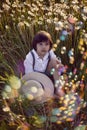 funny happy a beautiful boy child sit in hat on a field with white dandelions at sunset in summer. soap bubbles are Royalty Free Stock Photo