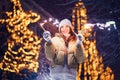 Funny happy caucasian girl burns sparklers by holiday illumination on new years eve