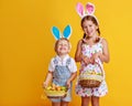 Funny happy children with easter eggs and bunny ears on yellow Royalty Free Stock Photo