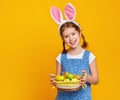 Funny happy child girl with easter eggs and bunny ears on yellow Royalty Free Stock Photo